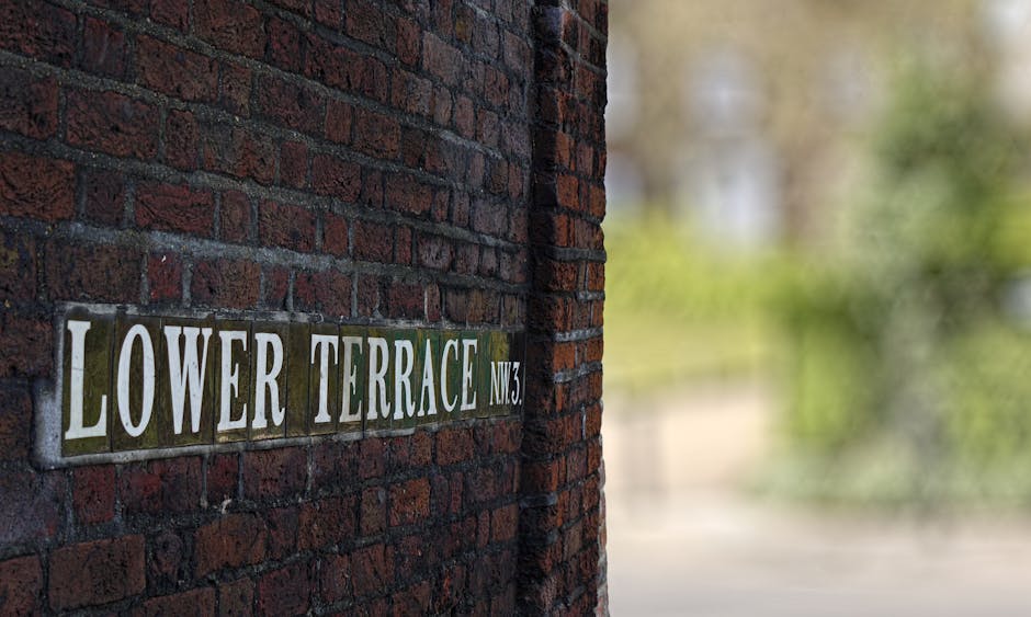 A row of white terraced houses with black wrought iron railings and decorative fencing along a paved sidewalk in Fleet Street terraces, Temple. The pavement consists of irregular stone slabs, some sho